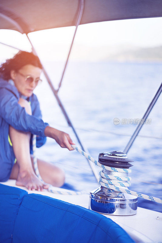 Woman pulling the ropes of sailing winch